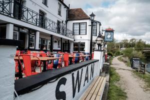 ein Restaurant mit roten Stühlen und einer Uhr an der Wand in der Unterkunft The Swan Hotel in Staines