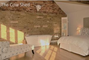 1 dormitorio con cama y bañera junto a una pared de ladrillo en The Coach House Denton, en Grantham