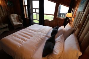 uma cama com almofadas num quarto com janelas em Brekkestranda Fjordhotel em Brekke