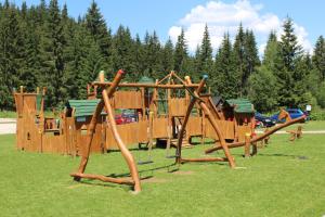 a playground with wooden play equipment in a park at Penzión Kohútik in Oravská Lesná