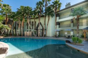 a swimming pool in front of a hotel with palm trees at Tahiti All-Suite Resort in Las Vegas