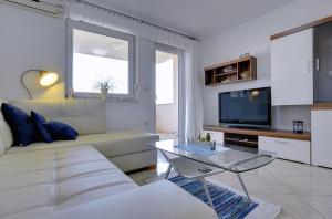 a living room with a white couch and a tv at Apartment Frlan in Ližnjan
