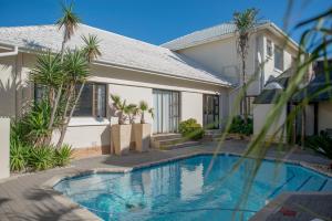 a villa with a swimming pool in front of a house at Palm Beach Guesthouse in Port Elizabeth