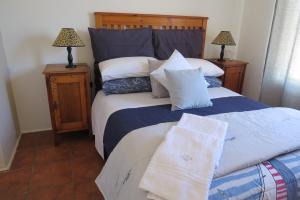 a bedroom with a bed with blue and white pillows at Chamomile Cottage 2 in Muizenberg
