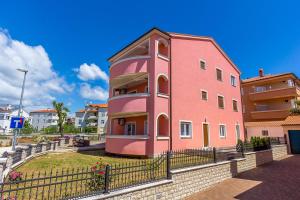 un edificio rosa con una valla delante en Apartments Marich en Medulin