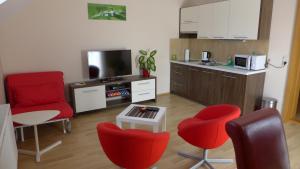 sala de estar con sillas rojas y cocina en Penzion Park - 2 izbové apartmány, en Nové Mesto nad Váhom