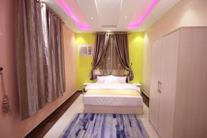 a bedroom with a bed with a window and purple lights at Nakhil Moon Serviced Apartments in Wadi Al Dawasir