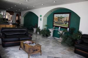 モレリアにあるEstanza Hotel & Suitesのソファ、テーブル、絵画のあるロビー