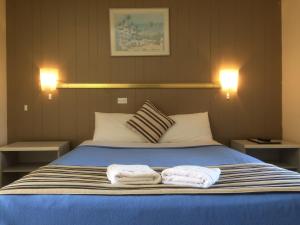 1 dormitorio con 1 cama con 2 toallas en Riverview Motor Inn, en Taree