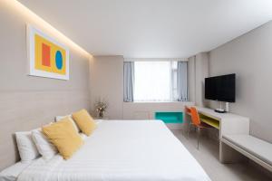 a white bedroom with a bed and a tv at New Seoul Hotel Myeongdong in Seoul