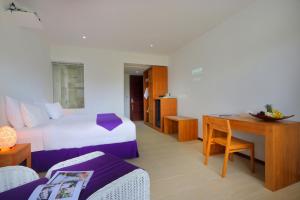 a hotel room with a bed and a desk and a room at Anema Wellness & Resort Gili Lombok - Diving Center PADI in Tanjung