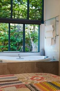 a bathroom with a tub and a large window at Ashwood Cottages in Bright