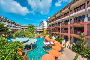 an outdoor pool with orange umbrellas next to a hotel at Kata Sea Breeze Resort - SHA Plus in Kata Beach