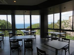 a restaurant with tables and chairs and large windows at Grampus Sea in Shirahama
