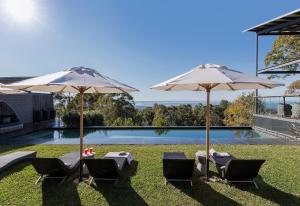 two umbrellas and two chairs and a swimming pool at Spicers Sangoma Retreat - Adults Only in Kurrajong