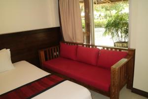 a red couch in a room with a window at Palita Lodge - SHA Plus in Haad Rin