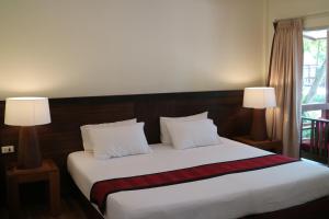 a bedroom with a large white bed with two lamps at Palita Lodge - SHA Plus in Haad Rin