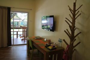 a room with a table and a tv on the wall at Palita Lodge - SHA Plus in Haad Rin