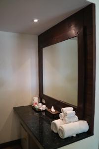 a bathroom with a mirror and towels on a counter at Palita Lodge - SHA Plus in Haad Rin