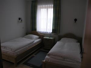 two beds in a small room with a window at Landgasthof und Hotel Forchhammer in Pliening