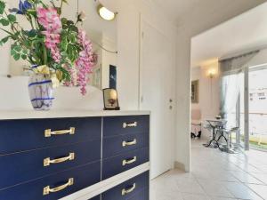 Una cómoda azul con un jarrón de flores. en Boite d'Amour, en Cannes