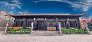 a building with a gate and stairs in front of it at Pingyao Elsewhere Gongji Hotel in Pingyao