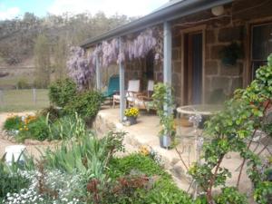Woodvale at Cooma في كوما: شرفة منزل به الزهور والنباتات