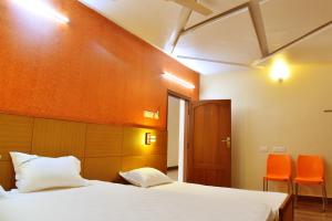 a bedroom with a bed and two orange chairs at Hotel Ganga Tamilnadu in Nāgercoil