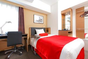 a bedroom with a bed with a desk and a red blanket at HOTEL MYSTAYS Kamata in Tokyo