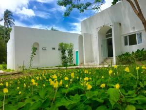 a white building with a field of yellow flowers at Sense of Yanui in Nai Harn Beach