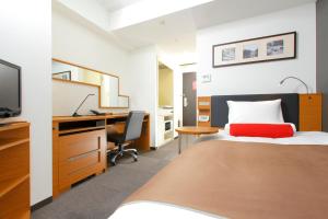 a bedroom with a bed and a desk and a computer at HOTEL MYSTAYS Kamata in Tokyo