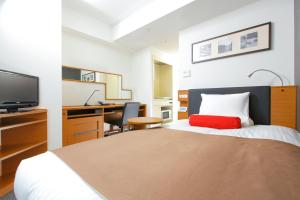 a bedroom with a bed with a red pillow and a desk at HOTEL MYSTAYS Kamata in Tokyo