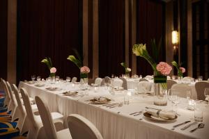 une grande table avec des tables et des chaises blanches ainsi que des fleurs dans l'établissement Wanda Realm Huaian, à Huai'an