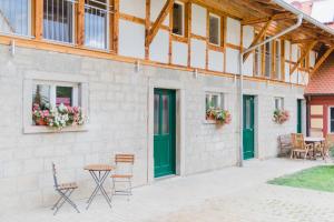 a building with green doors and chairs and a table at Hellbachhof in Equarhofen