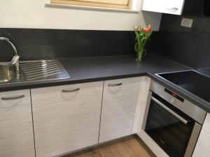 a kitchen with white cabinets and a black counter top at Apartment Lapanja in Slap ob Idrijci