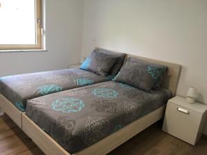 uma cama com lençóis e almofadas cinzentos e azuis em Apartment Lapanja em Slap ob Idrijci