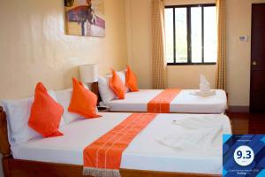two beds in a hotel room with orange pillows at Haisa Apartment in Coron