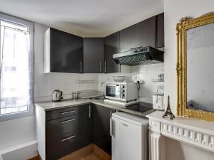パリにあるウェルキーズ アパートメント パリ リヴォリのキッチン(白黒のキャビネット、電子レンジ付)