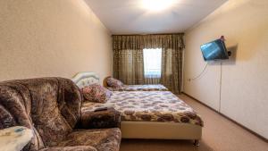 a bedroom with a bed and a couch and a tv at Apartments at Michurina 15 in Kemerovo