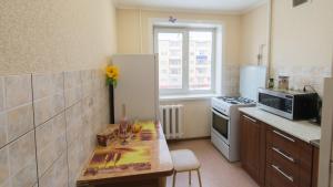 a kitchen with a refrigerator and a table in it at Apartments at Michurina 15 in Kemerovo