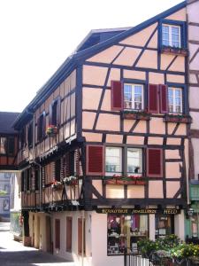 um edifício em enxaimel com persianas vermelhas e janelas em Aux Bijoux De Colmar - 1 Parking Gratuit em Colmar