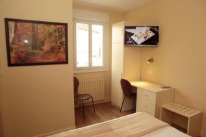 um quarto com uma cama, uma secretária e uma janela em Hôtel - Restaurant des Voyageurs em Ambazac