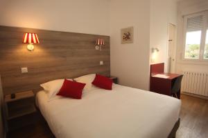 1 dormitorio con 1 cama blanca y 2 almohadas rojas en Hôtel - Restaurant des Voyageurs en Ambazac
