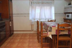 cocina con mesa con sillas y ventana en Casa Rural Flor, en Vadocondes