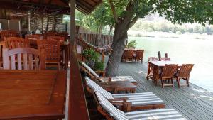 a wooden deck with tables and chairs and a tree at Dalyan Pension in Dalyan