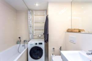 a bathroom with a washing machine next to a bath tub at Baranova Apartments in Prague