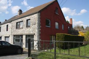 a red and white brick house with a car parked in front at Appartement Vallee de la Meuse - Esc'Appart in Blaimont