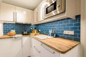 een keuken met witte kasten en blauwe tegels bij Haus am Meer-Ferienwohnungen Sylt in Hörnum