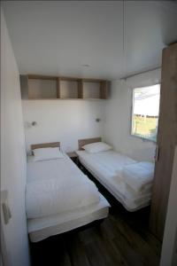 2 Betten in einem kleinen Zimmer mit Fenster in der Unterkunft Camping Panorama in Bourscheid
