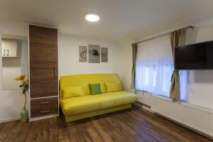 a yellow couch in a living room with a tv at Vila Aleksandra in Zlatibor